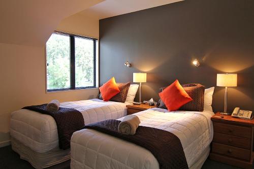 a bedroom with two beds with orange pillows at Drifters Inn in Hanmer Springs