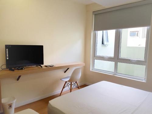 a bedroom with a desk with a tv and a window at The Leaf House in Manila