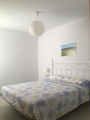 a white bedroom with a bed and a lamp at Ses Sivines 25 in Ciutadella