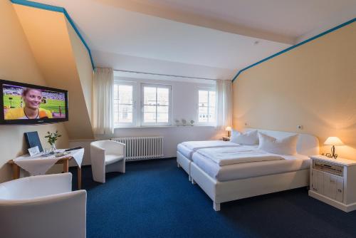 a bedroom with a bed and a flat screen tv at Hotel am Wind in Großenbrode