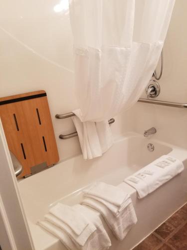 y baño con bañera y toallas blancas. en Ramada by Wyndham Williston, en Williston