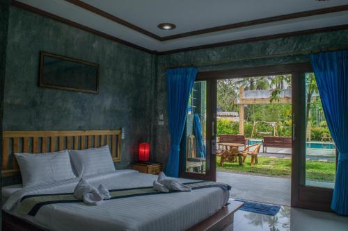 a bedroom with a bed and a sliding glass door at Wonderland Healing Center in Thongsala