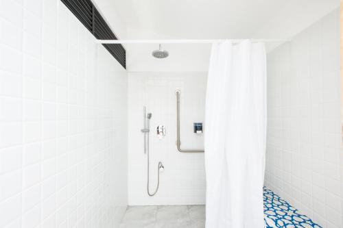 a shower in a white bathroom with a shower curtain at Capital Hostel de Ciudad in San José