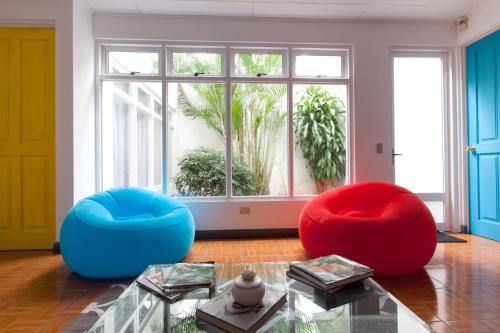 two blue and red chairs in a room with a window at Capital Hostel de Ciudad in San José