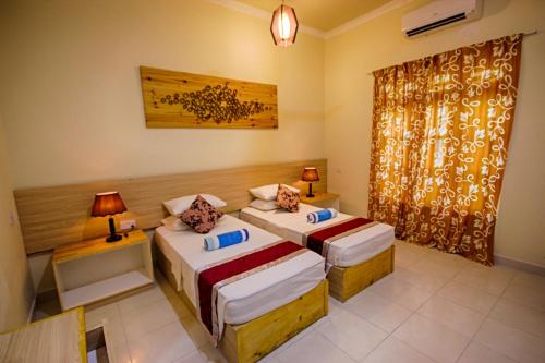 a hotel room with two beds and a window at Fulidhoo Ihaa Lodge in Fulidhoo