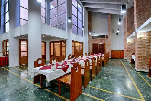a row of tables in a large room with windows at Indo Hokke Hotel in Rājgīr