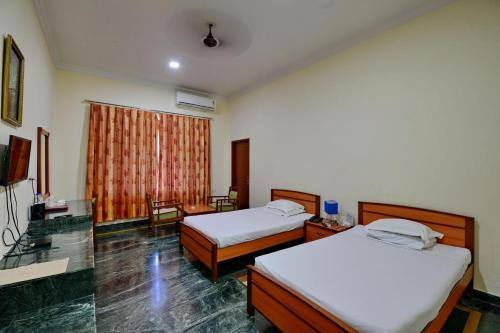 a hotel room with two beds and a television at Indo Hokke Hotel in Rājgīr