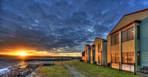 a sunset over the water next to buildings at Stanley Village Waterfront Accommodation in Stanley