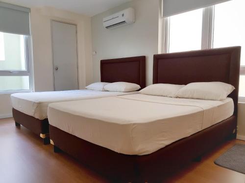 two twin beds in a room with two windows at The Leaf House in Manila