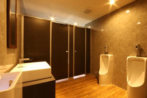 baño con 2 urinarios, lavabo y espejo en Kannabe Highland Hotel en Toyooka