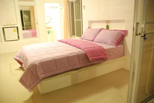 a bed with pink and pink pillows in a room at Baantantara in Suan Phung