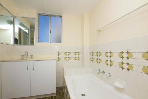 La salle de bains blanche est pourvue d'une baignoire et d'un lavabo. dans l'établissement Beachpoint, Unit 401, 28 North Street, à Forster