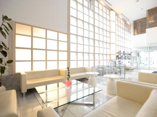eine Lobby mit weißen Möbeln und einem Glastisch in der Unterkunft APA Hotel Mito-eki Kita in Mito