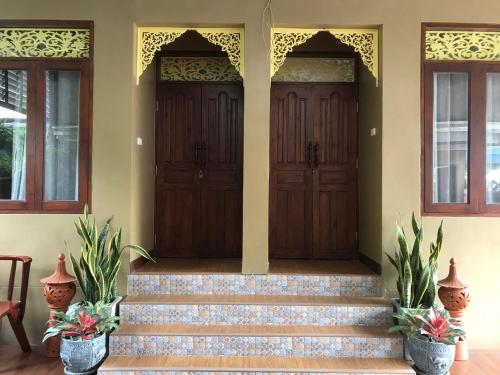 a house with two wooden doors and stairs at Banchan Hostel in Phra Nakhon Si Ayutthaya