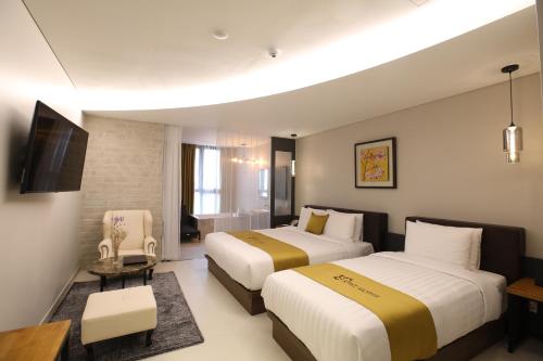 um quarto de hotel com duas camas e uma televisão em Rest Hotel em Gimpo