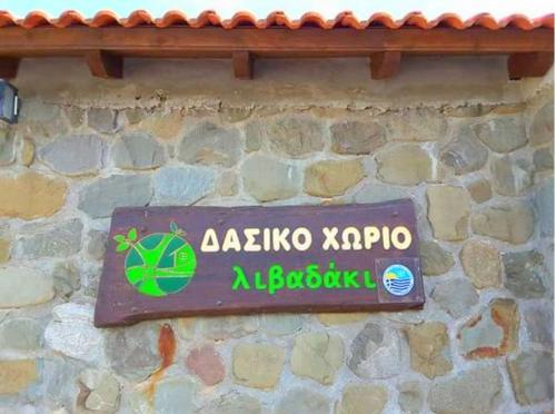 a sign on the side of a stone wall at Livadaki Village in Megáli Kápsi
