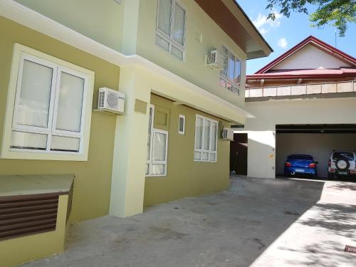 ein gelbes Haus mit Garage und Auto in der Unterkunft The Leaf House in Manila