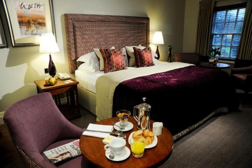 a hotel room with a bed and a table with food on it at The Arden Hotel Stratford - Eden Hotel Collection in Stratford-upon-Avon