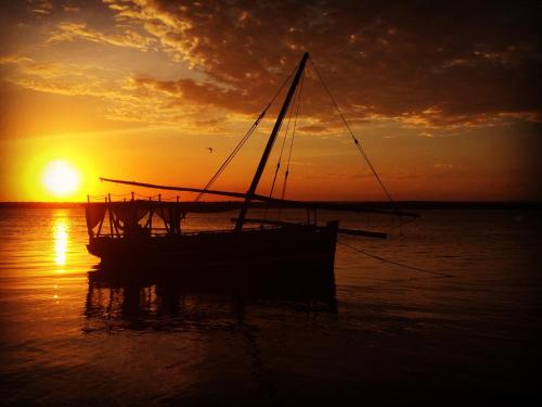 a boat sitting in the water at sunset at Rock and Sea Resort in Watamu