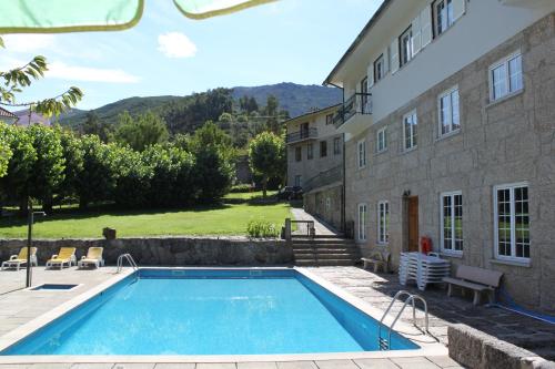 a swimming pool in front of a building at Casa da Ribeira in Alvoco da Serra