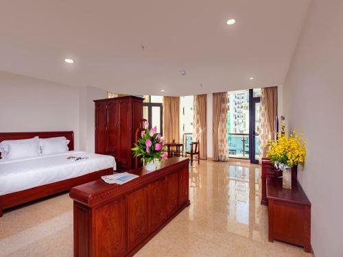 a bedroom with a bed and a table with flowers at Red Sun Nha Trang Hotel in Nha Trang