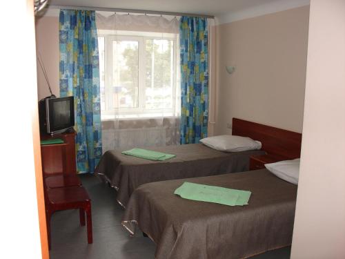 a room with two beds and a tv and a window at Hotel Berezka in Vyshny Volochyok