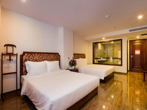 a hotel room with two beds and a window at Red Sun Nha Trang Hotel in Nha Trang