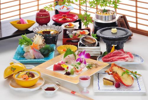 a table topped with plates of food and chopsticks at Hotel Sanrakuso in Shirahama
