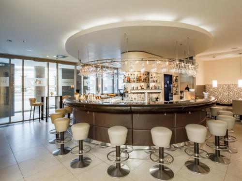 a bar in a restaurant with stools at Lindner Hotel Vienna Am Belvedere, part of JdV by Hyatt in Vienna