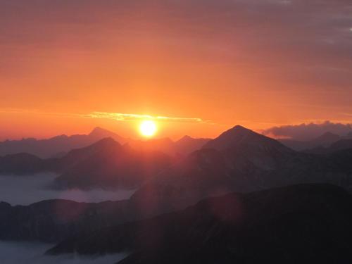 a sunset over a mountain range with the sun setting at Haus Anni in Radstadt