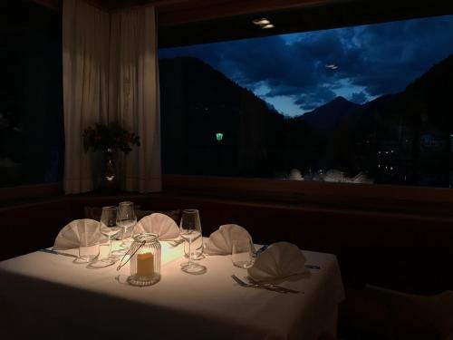 a table with a white table cloth and glasses and a window at Sporthotel Europa Sul Lago in Alleghe