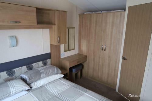 a small bedroom with a bed and a wooden cabinet at West Loch Shores in Tarbert
