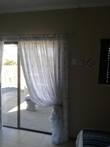 a bedroom with a window with a curtain at Elim Guesthouse in Keimoes