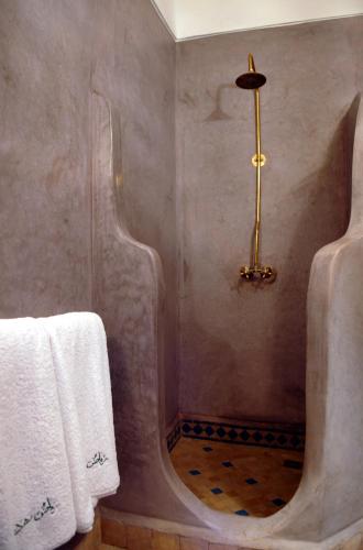 a bathroom with a shower with white towels and a tub at Riad Mehdia in Marrakech