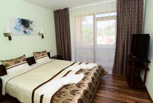 a bedroom with a bed and a window and a television at Guesthouse Nefertiti in Smolyan