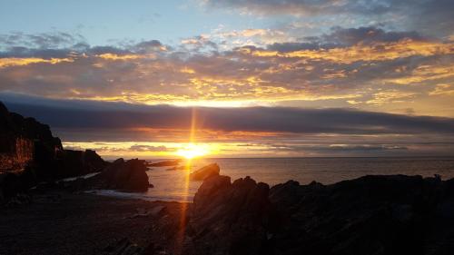 a sunset over the ocean with rocks on the beach at Rocky Cove Bed and Breakfast in Ilfracombe