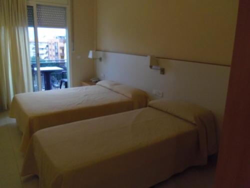 two beds in a hotel room with a window at Hotel Sant Jordi in Segur de Calafell