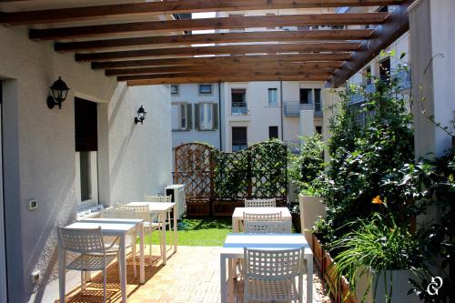 un patio con tavoli, sedie e pergolato in legno di B&B Fanzago a Bergamo