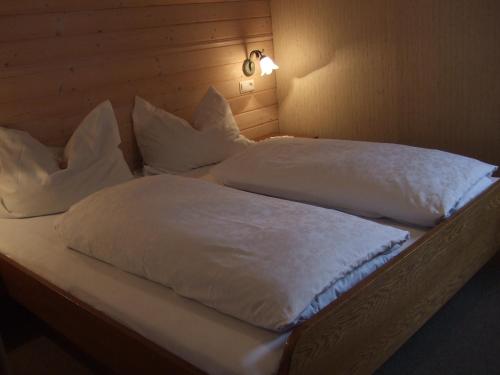 Una cama con sábanas blancas y almohadas. en Ferienwohnungen Trattner, en Mauterndorf