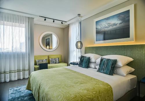 a bedroom with a large bed and a mirror at Tal By The Beach - An Atlas Boutique Hotel in Tel Aviv
