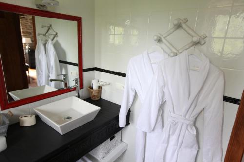 La salle de bains est pourvue d'un lavabo et d'un peignoir blanc. dans l'établissement Maison Aretxola, à Sare