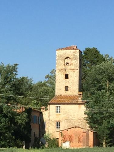 an old building with a tower on top of it at Capannacce Organic and Horse Farm in Rapolano Terme