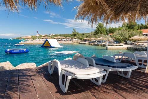 einen Tisch und Stühle auf einer Terrasse neben dem Wasser in der Unterkunft Holiday Park Mandrice in Mandre