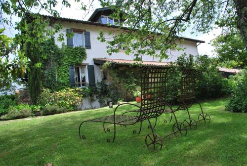 a metal bench sitting in the grass in front of a house at Maison Aretxola in Sare