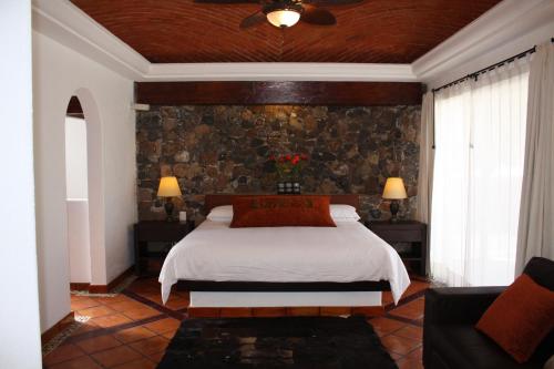 - une chambre avec un lit et un mur en pierre dans l'établissement Hotel Villa Mexicana Golf & Equestrian Resort, à Villa del Pueblito