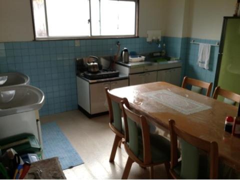 uma cozinha com uma mesa de madeira e um lavatório em Minshuku Toshi em Yakushima