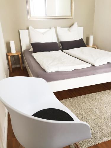 a bed with white sheets and a chair in a room at Ferienwohnung an der historischen Stadtmauer in Rostock
