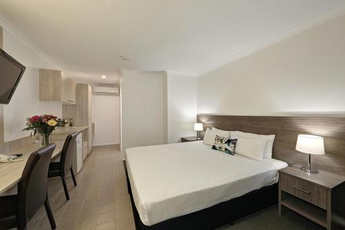 a hotel room with two beds and a table at Smart Motels Bert Hinkler in Bundaberg