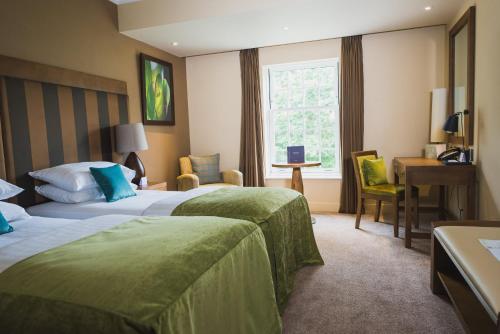 a hotel room with two beds and a desk at Spa Hotel at Ribby Hall Village in Wrea Green