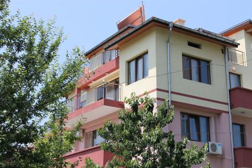 a pink and white building with trees in the foreground at Guest House Dara in Tsarevo